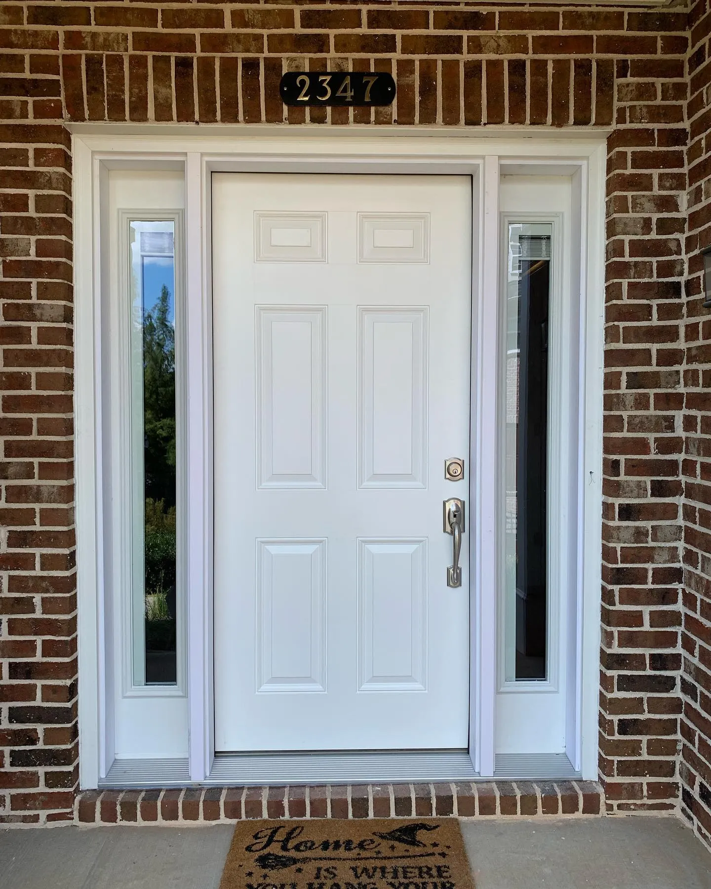 New white front door with sidelights fitted into a brick facade