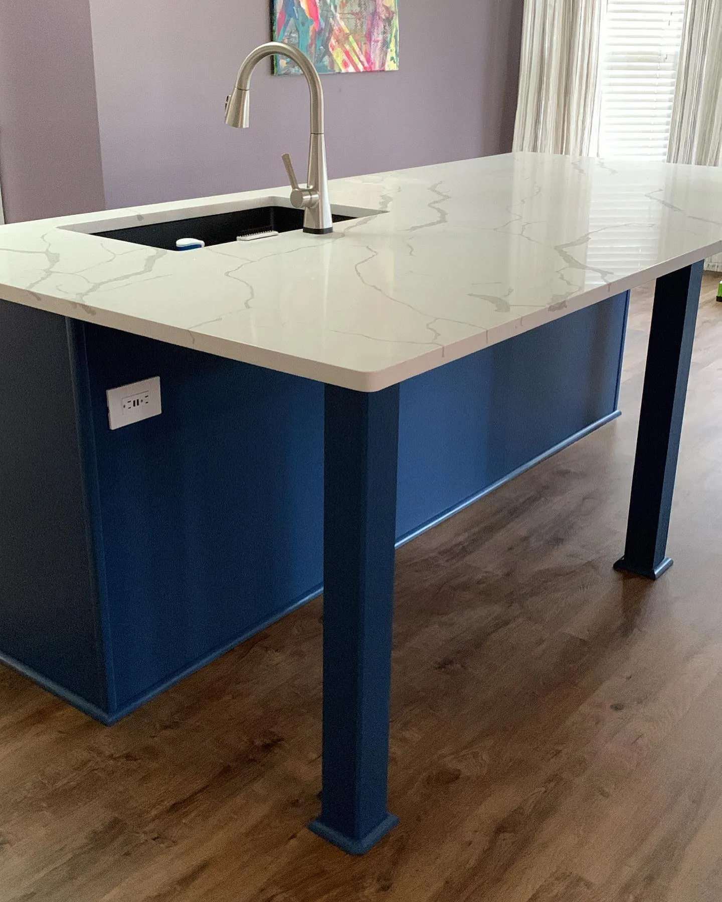 Blue custom kitchen island with a white waterfall stone top