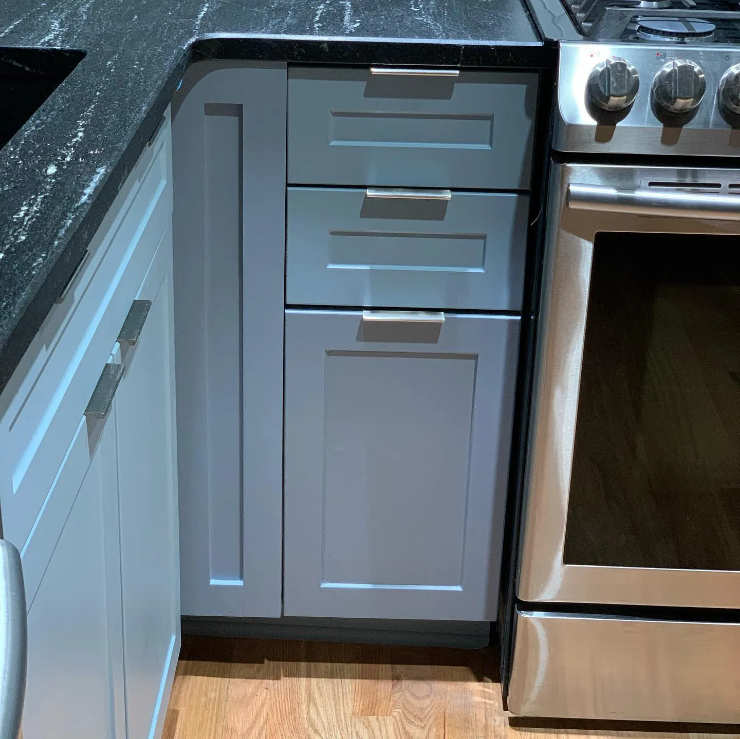 Grey shaker kitchen cabinetry with brushed steel hardware beside a range