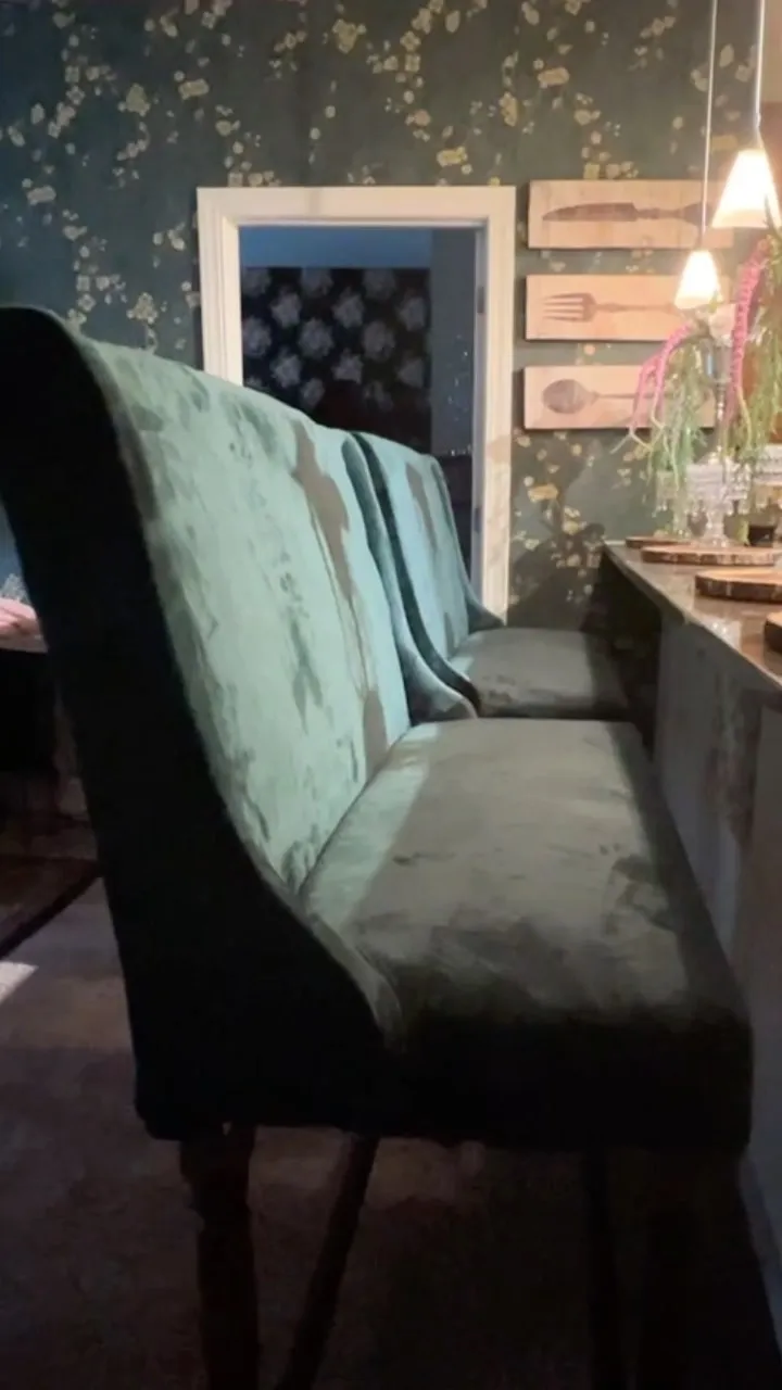 Dining nook with patterned wallpaper and upholstered banquette seating
