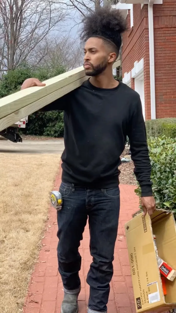 Mhaliek Porter carrying lumber up a front path